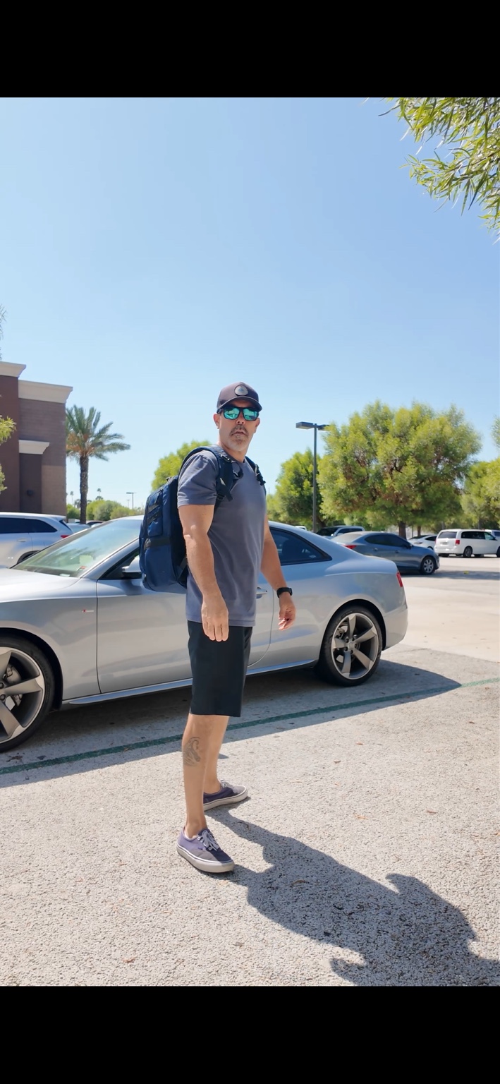 Brian Moreno standing beside a silver Audi coupe in a parking lot